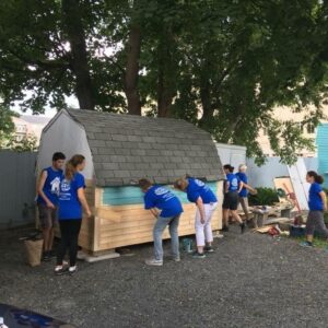 Volunteers in Fredericton working on the siding of a shed.
